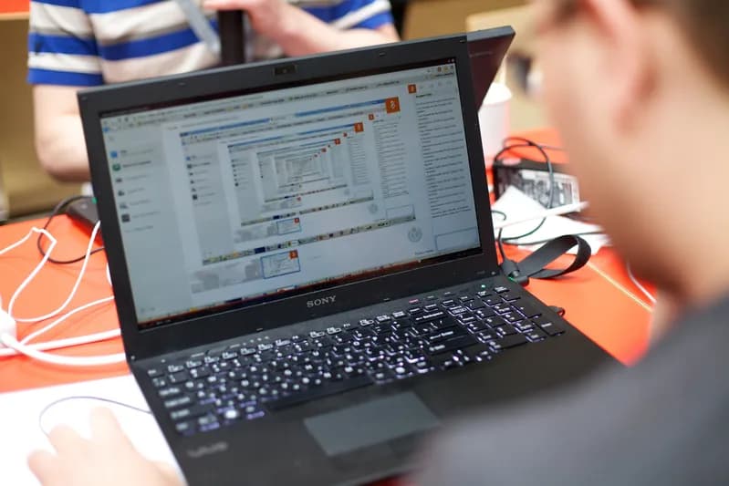 Developers working on laptops at tables during a hackathon event