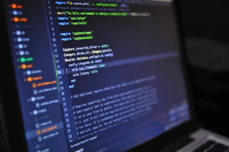 Laptop on a desk showing source code with syntax highlighting in a dark editor theme