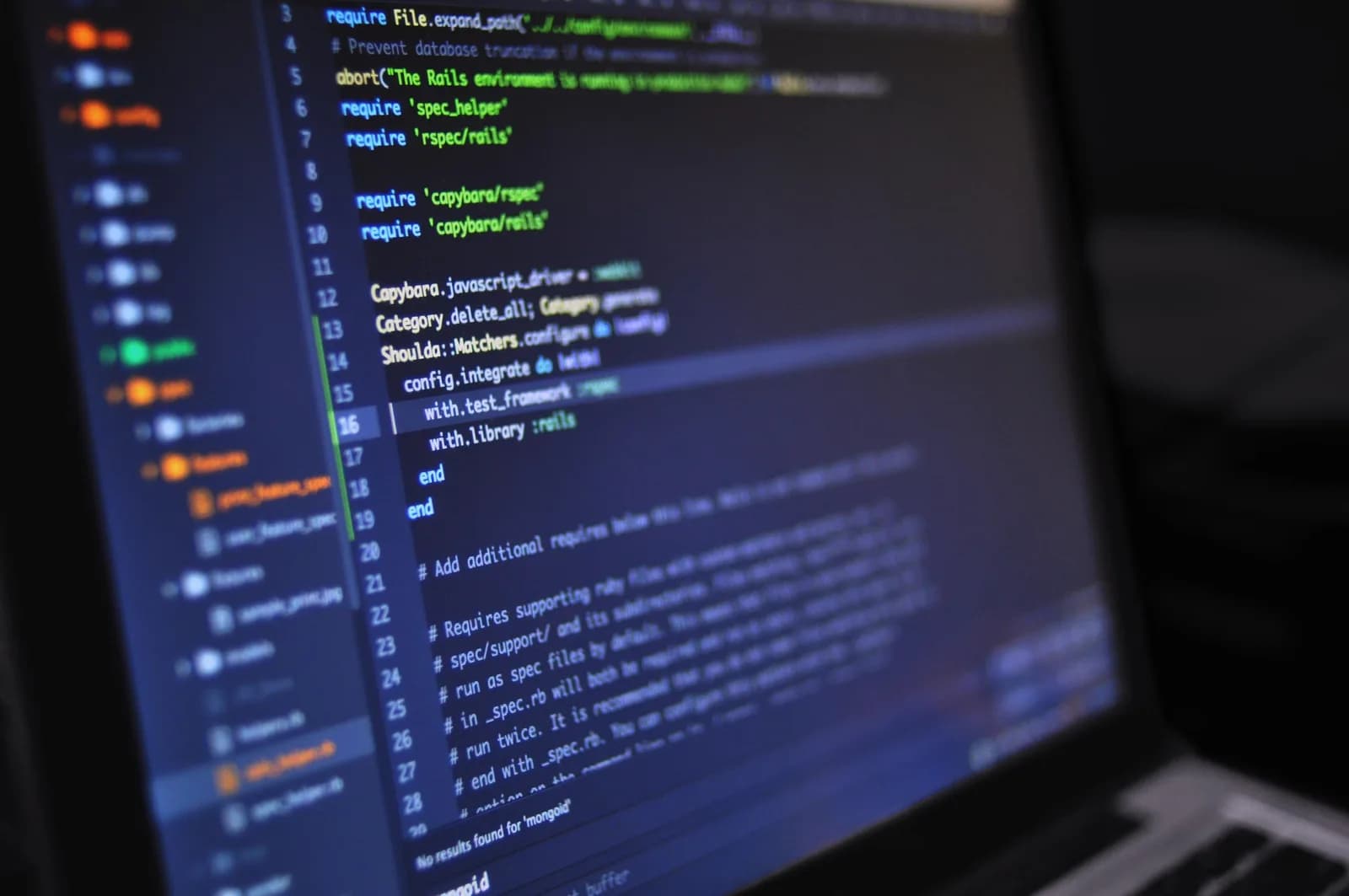 Laptop on a desk showing source code with syntax highlighting in a dark editor theme