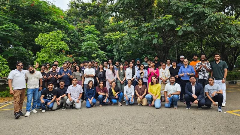Large group of hackathon participants posing outdoors in front of trees at an event in Hyderabad, India