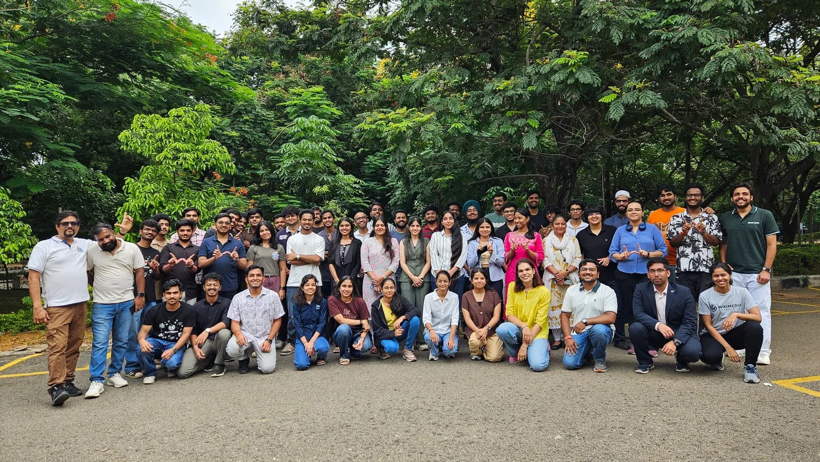 Large group of hackathon participants posing outdoors in front of trees at an event in Hyderabad, India