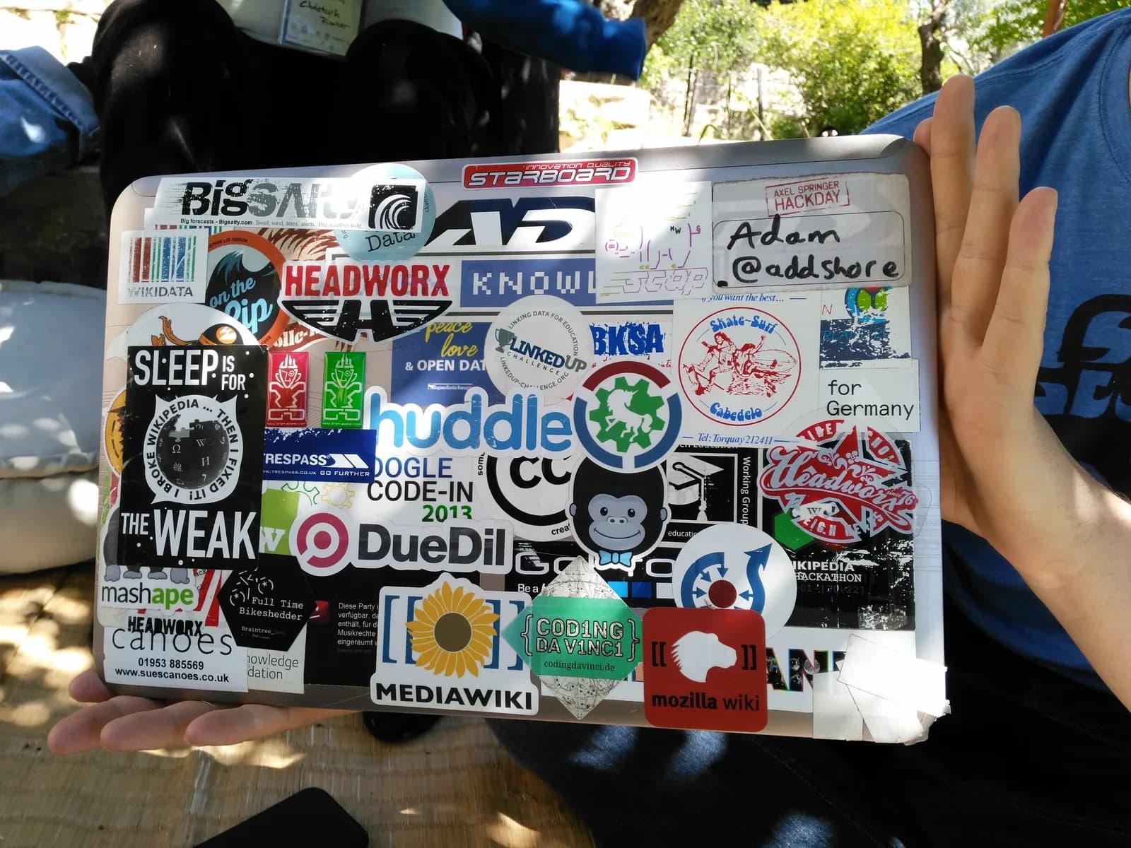 Developer laptop lid covered in stickers from software projects at a hackathon