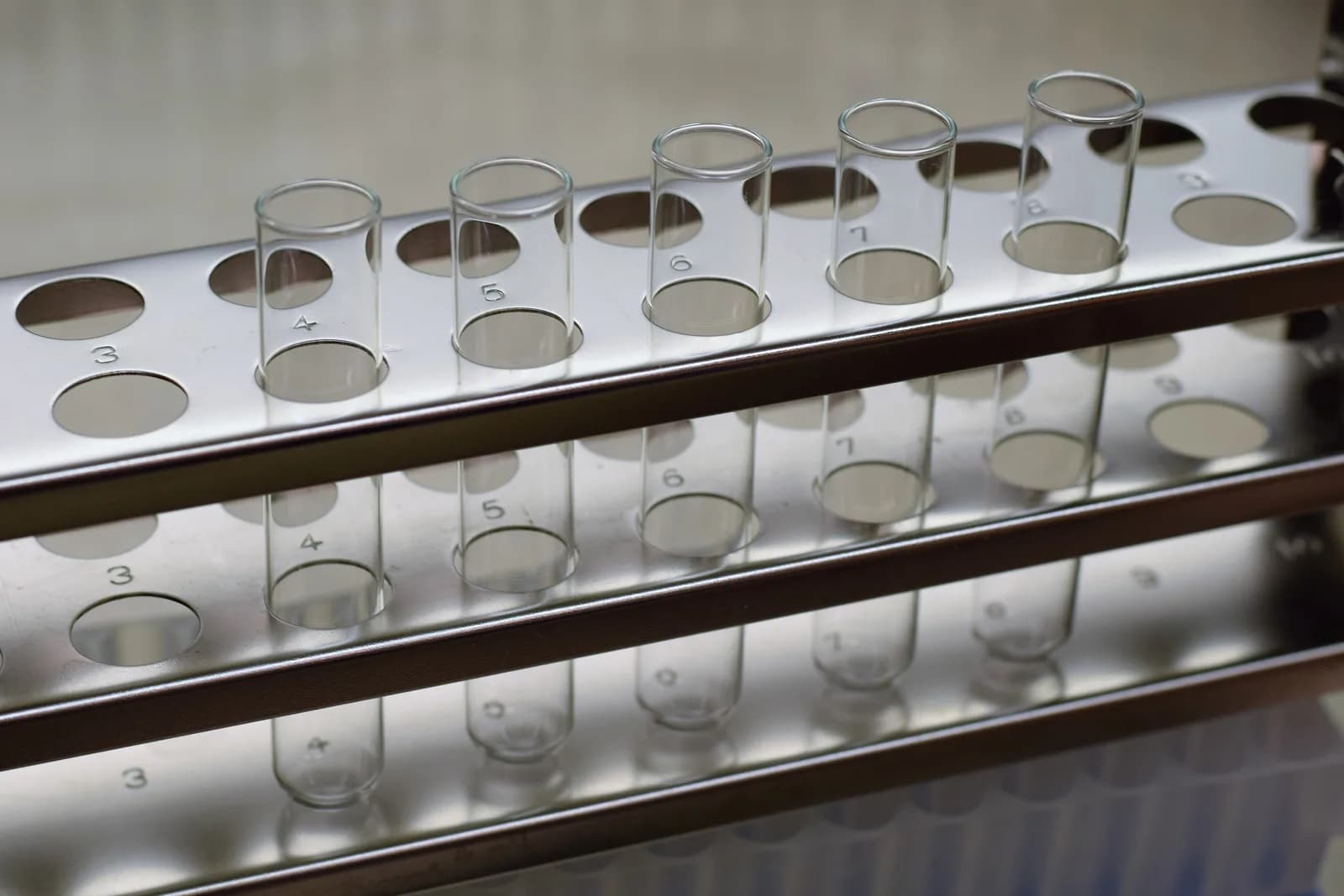 Row of clean glass test tubes standing in a polished metal rack