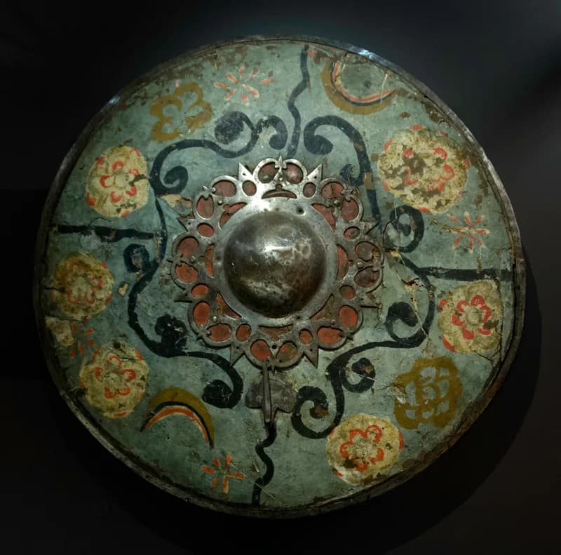 Round sixteenth-century iron and leather shield with painted decoration and a central metal boss