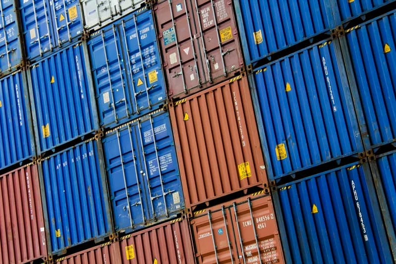 Stacked blue and rust-red steel shipping containers photographed at an angle in the Port of Rotterdam
