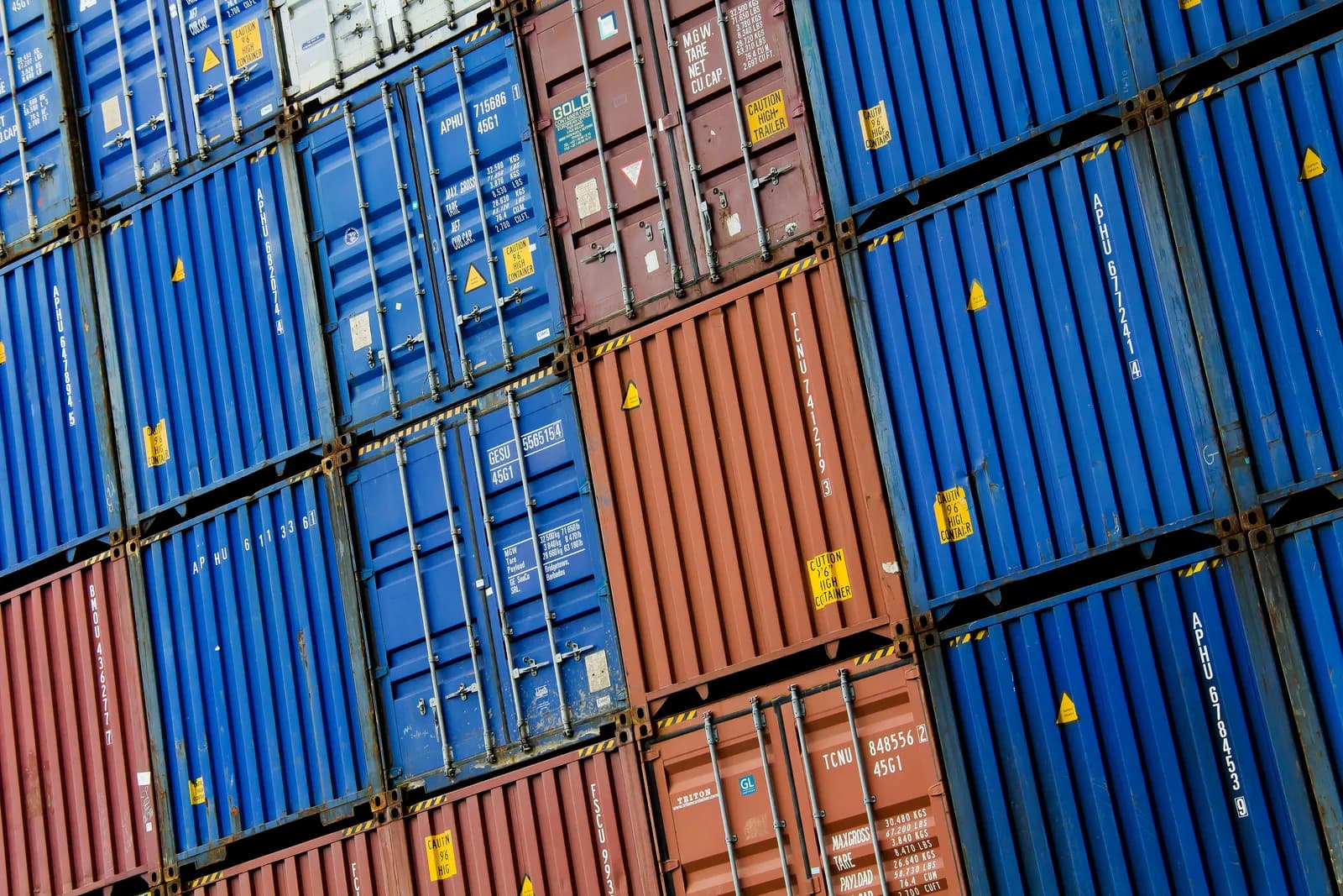 Stacked blue and rust-red steel shipping containers photographed at an angle in the Port of Rotterdam