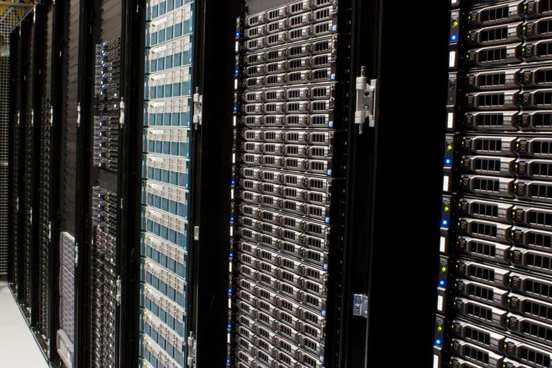 Row of black server racks filled with rack-mounted servers in a data centre aisle
