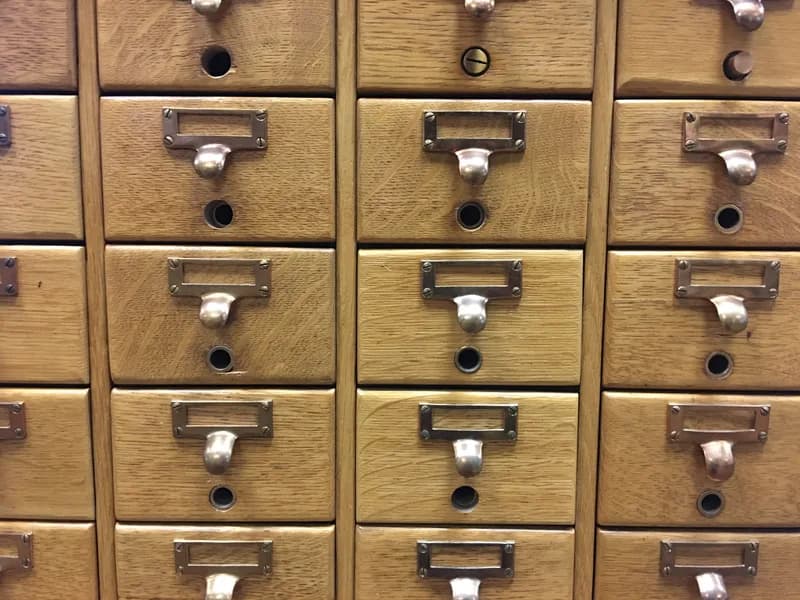Close-up of wooden library card catalogue drawers with brass label holders and pull handles