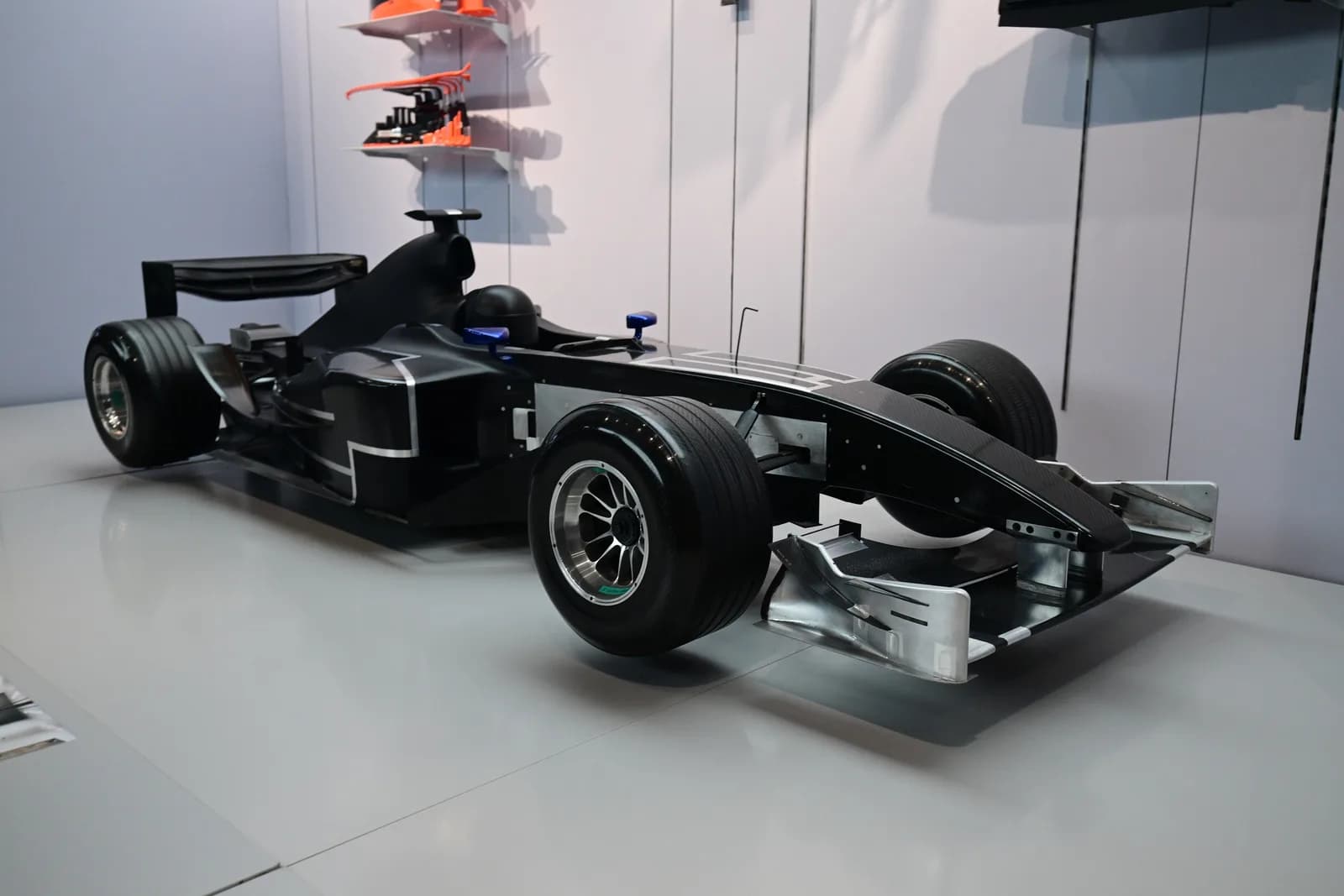 Black Formula 1 wind tunnel test model car displayed on a white floor at an exhibition