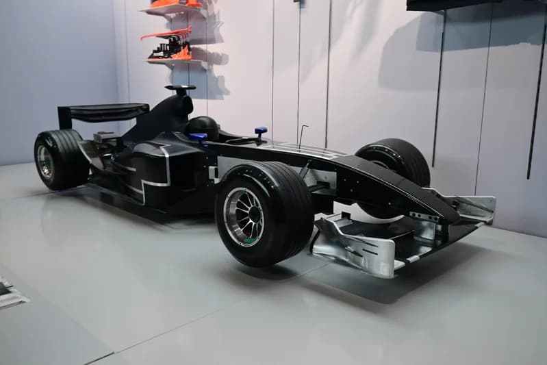 Black Formula 1 wind tunnel test model car displayed on a white floor at an exhibition