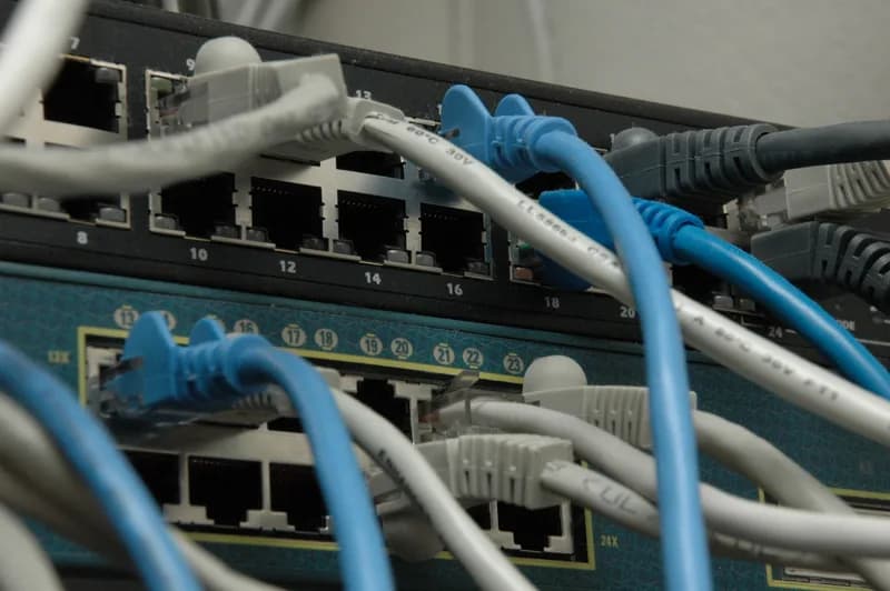 Close-up of two stacked network switches with blue and grey Ethernet cables plugged into their numbered ports