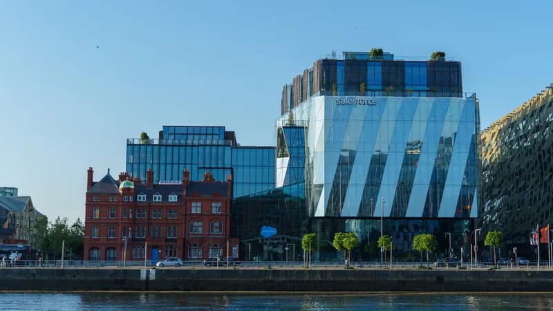 Glass Salesforce office building with the Salesforce name near the top, beside a red-brick building on the River Liffey quays in Dublin