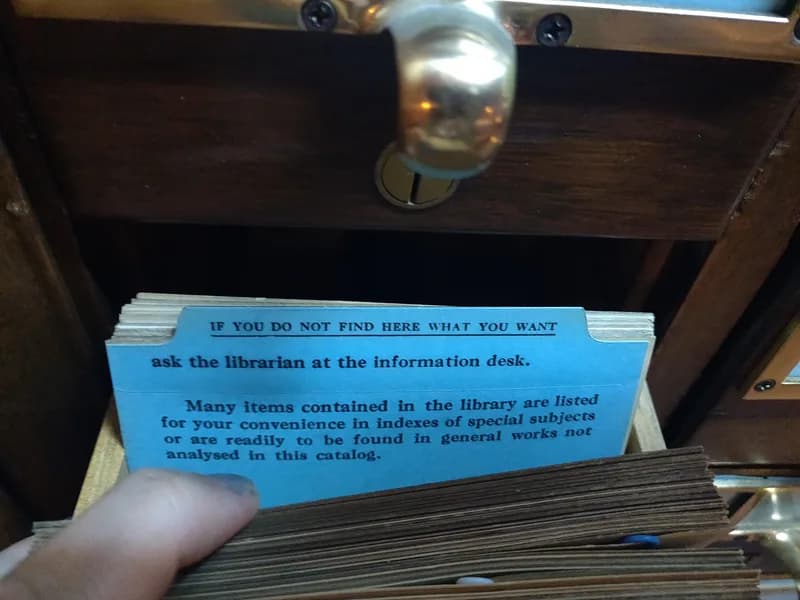 An open card catalogue drawer at the Indiana State Library showing a blue card that reads: If you do not find here what you want, ask the librarian at the information desk