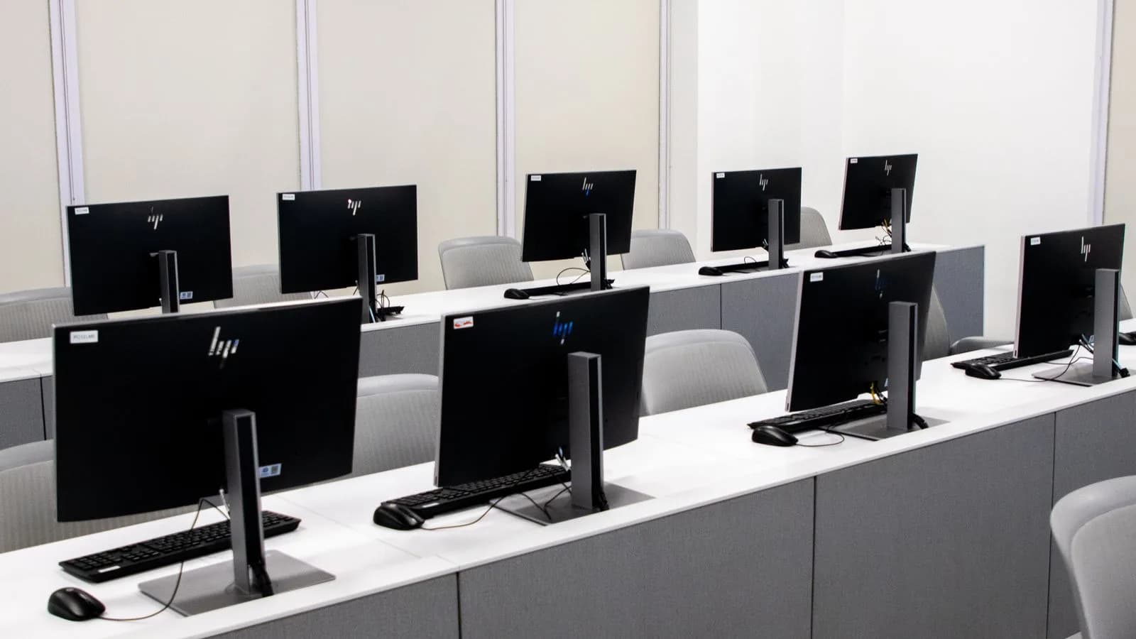 Empty computer classroom with rows of desktop workstations.