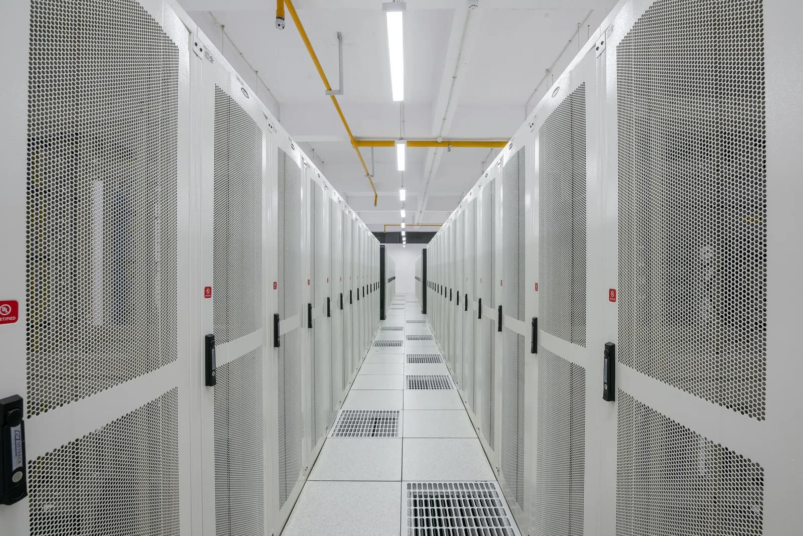 Long aisle of white server racks in a data centre.
