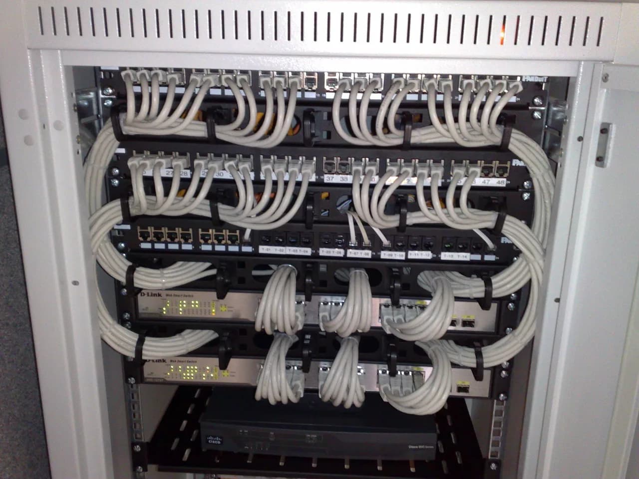 Rack of Ethernet switches and patch panels with network cables.